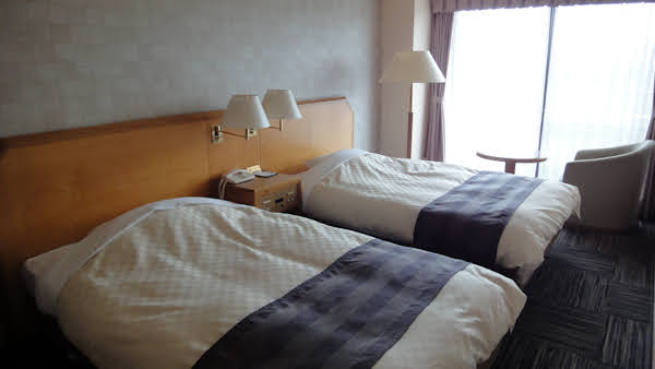 hotel suite bedroom with two queen size beds and a small table and chair near a window